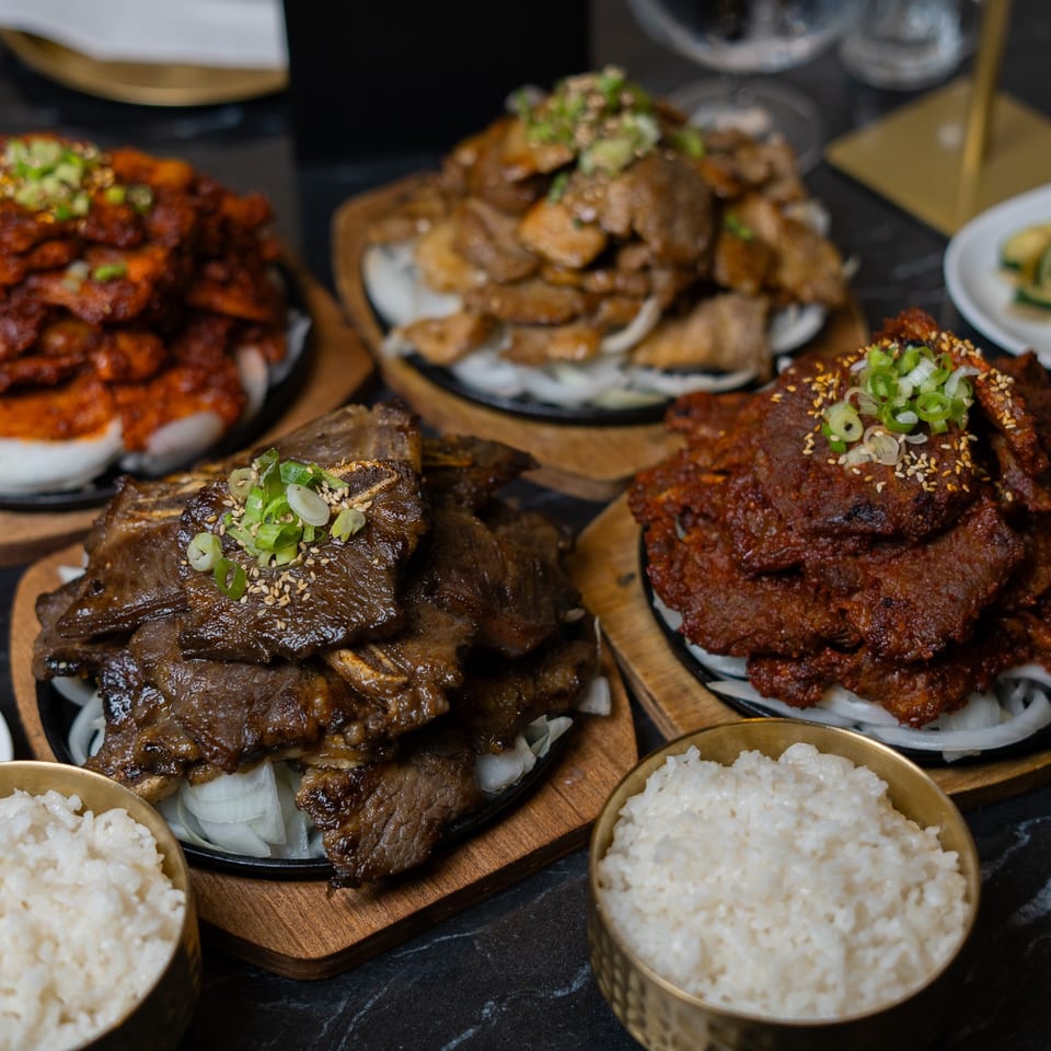 A feast of Korean BBQ dishes, including spicy pork, marinated short ribs, and various banchan, with rice.